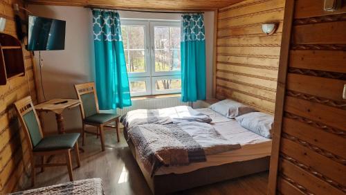 ein Schlafzimmer mit zwei Betten und einem Fenster mit blauen Vorhängen in der Unterkunft Diablak in Zawoja