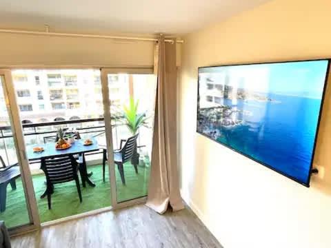 - un salon avec une table à manger et une grande fenêtre dans l'établissement Le Cannes Beach 408 - cosy avec balcon & piscine, à Cannes
