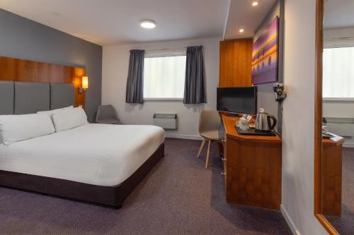 una camera da letto con un letto, una scrivania e una televisione di The Magnum Hotel Sunderland, Sure Hotel Collection by Best Western a Sunderland