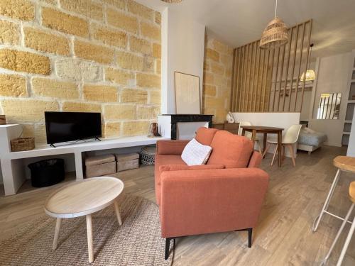 a living room with an orange chair and a tv at Gabriel T1 Bis 35m2 - 1 Chambre 1 Salle de Bain in Libourne