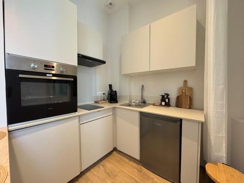 a kitchen with white cabinets and a black microwave at Gabriel T1 Bis 35m2 - 1 Chambre 1 Salle de Bain in Libourne
