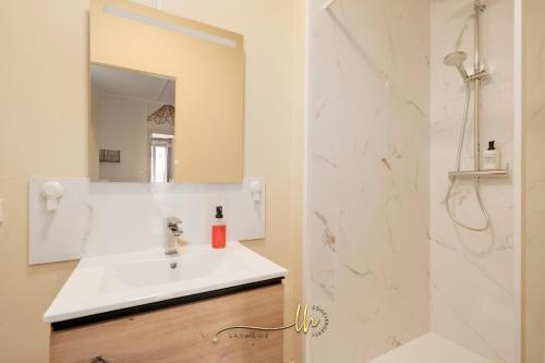 une salle de bain blanche avec un lavabo et une douche dans l'établissement Lumière & Calme - Le Repos d'Ingrid, à Nancy