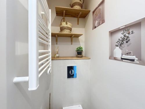 La salle de bains est pourvue de murs blancs ainsi que de toilettes et d'étagères blanches. dans l'établissement Cozy studio with garden and parking in Cannes, à Cannes