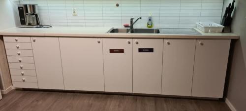 a kitchen with white cabinets and a sink at Koselig rom i sentrum Gratis Wifi og Parkering Rom 3 1 etg in Narvik