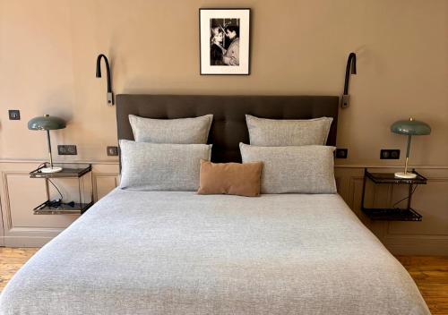 une chambre avec un grand lit avec des oreillers dans l'établissement L'Hotel Particulier, à Louhans