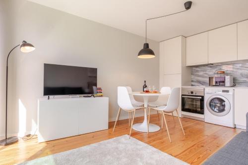 a white kitchen with a table and white appliances at HostWise – Modern & Cozy Flat | Near the Beach in Matosinhos