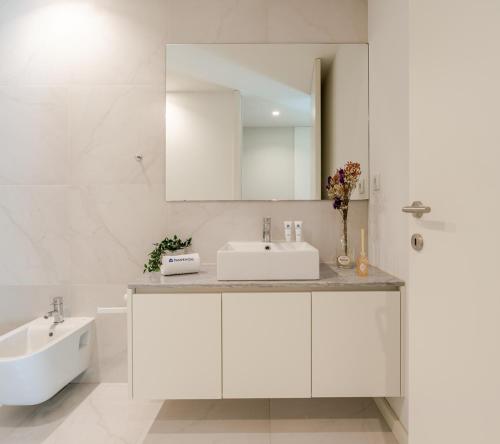 a white bathroom with a sink and a mirror at HostWise – Modern & Cozy Flat | Near the Beach in Matosinhos