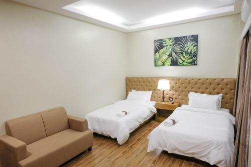 a hotel room with two beds and a couch at Ambien's Place Residential Hotel in Dagupan