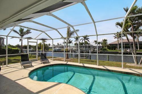 a swimming pool with a pergola next to a river at Chic & modern canal-front retreat with private pool - Azure Tides in Punta Gorda