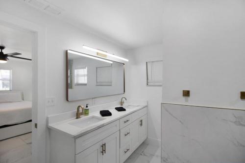 a white bathroom with a sink and a mirror at Chic & modern canal-front retreat with private pool - Azure Tides in Punta Gorda