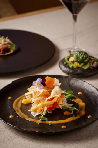 a plate of food on a table with a wine glass at Meltemi Blu - Adults Only in Perissa