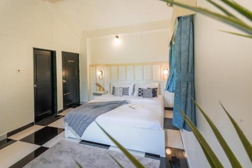 a bedroom with a white bed and a black and white floor at Ekostay Gold - Cosy Cove Villa in Lonavala
