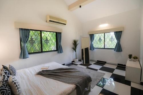 a bedroom with a bed and two windows at Ekostay Gold - Cosy Cove Villa in Lonavala
