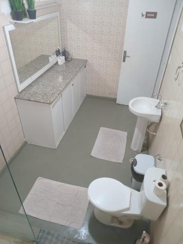 ein Badezimmer mit Toilette, Waschbecken und Spiegel in der Unterkunft Quarto a 150m da Praia do Farol da Barra II in Salvador