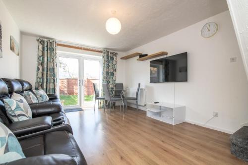 a living room with a couch and a tv and a table at Modern Two Bedroom House with Parking in Tipton