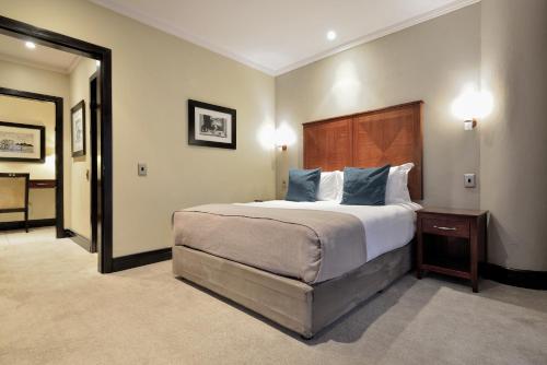 a bedroom with a large bed with blue pillows at Raphael Suites in Johannesburg