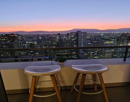 two stools on a balcony with a view of a city at Espectacular vista y ubicación in Santiago