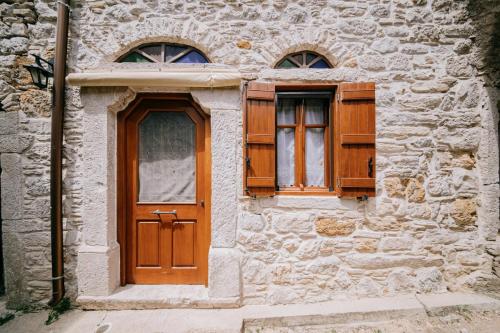 a building with a wooden door and two windows at Traditional house in Kalamoti Agios Georgios in Kalamoti