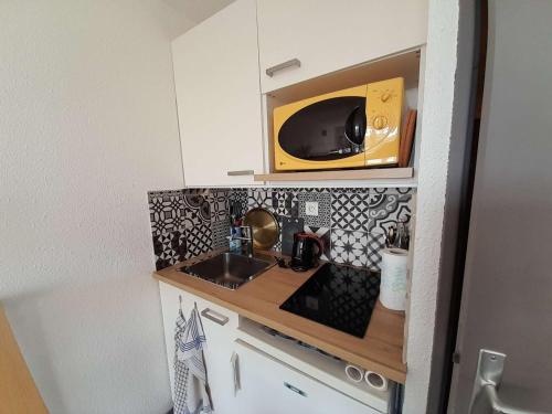 une petite cuisine avec un évier et un micro-ondes dans l'établissement Studio proche plage avec balcon, petit garage et animaux admis - FR-1-324-561, à Saint-Hilaire-de-Riez