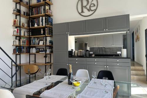 a dining room with a glass table and a kitchen at Architect-designed house close to beaches and shops in Rivedoux-Plage