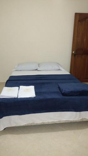 a bed with blue sheets and white towels on it at Casa de Descanso Zapatoca in Zapatoca