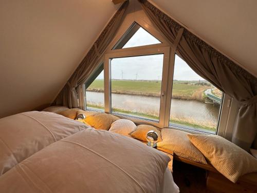 a bedroom with a large window with a view of a river at Großzügiges modernes Ferienhaus in Neuharlingersiel