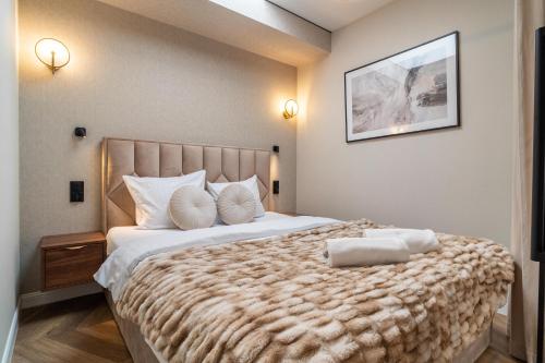 a bedroom with a large bed with a brown blanket at P R A T U M Pink&Blue Mikołajki Apartament Elegance z widokiem na jezioro in Mikołajki