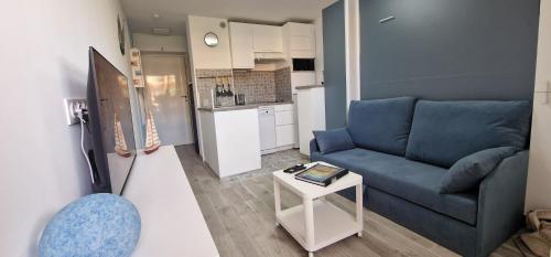 un salon avec un canapé bleu et une table dans l'établissement joli studio refait a neuf, à Bormes-les-Mimosas
