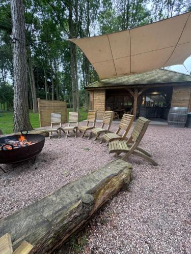 a group of chairs sitting around a fire pit at Riverside Cabins in Shrewsbury