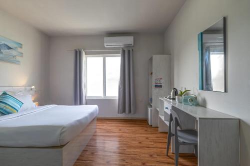 a hotel room with a large bed and a desk at Coquillage Inn in Gulhi