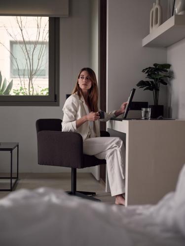 a woman sitting at a desk with a laptop at Bond Smart Living Suites in Athens