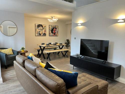 a living room with a couch and a flat screen tv at A Cozy Magical Retreat at Knightwood Oak, New Forest in Ower