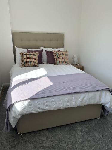 a bedroom with a bed with purple sheets and pillows at Quayside in Holyhead