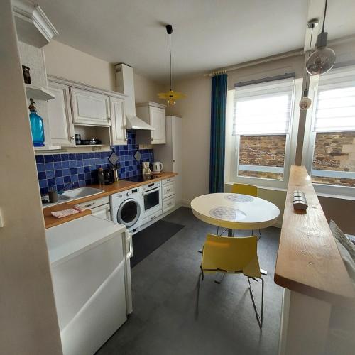 - une cuisine avec une table, une petite table, une table et des chaises dans l'établissement appartement chic et calme en plein centre-ville, à Paimpol