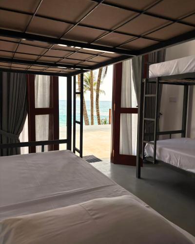 a bedroom with two bunk beds and a view of the beach at Surfing Tusker - Thalpe in Talpe