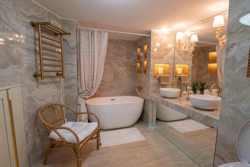 La salle de bains est pourvue de 2 lavabos, d'une baignoire et d'une chaise. dans l'établissement 2-bedroom luxurious apartment with balcony and parking, à Cannes