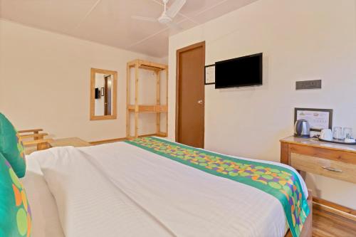 a bedroom with a bed and a tv on the wall at Treebo Vitasta Villa, Srinagar in Srinagar