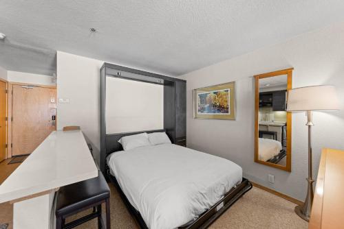 a small bedroom with a bed and a mirror at Palisades Tahoe Lodge Rentals Studio Loft #356 in Olympic Valley