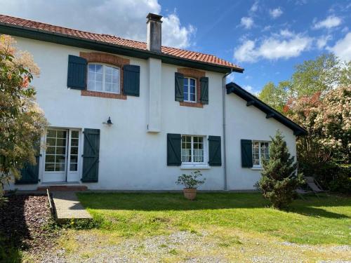 a white house with green shutters and a yard at Maison Narbay 2 p in Saint-André-de-Seignanx