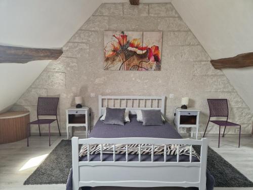 une chambre avec un lit blanc et deux chaises dans l'établissement Maison gîte proche du Château de Chambord, à Maslives