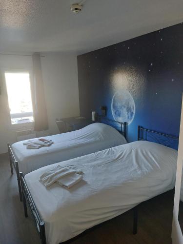 two beds in a room with a moon on the wall at Fasthotel in Jaux