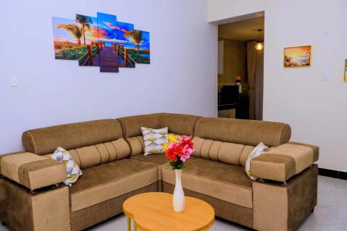 a brown couch with a vase of flowers on a table at Kampala Hilltop Haven 2 Bedroom Gem in Kampala