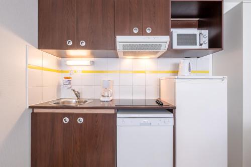 a small kitchen with a sink and a refrigerator at Comfort Aparthotel Les Hauts d'Annecy in Annecy