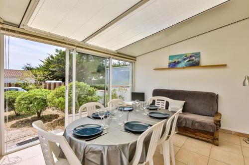 a dining room with a table and chairs and a couch at Le Temps de Vivre - Maison & dépendance in Notre-Dame-de-Monts