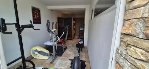 a hallway with a gym with exercise bikes and a stone wall at Bienvenue à la villa Bellavista in Pertuis