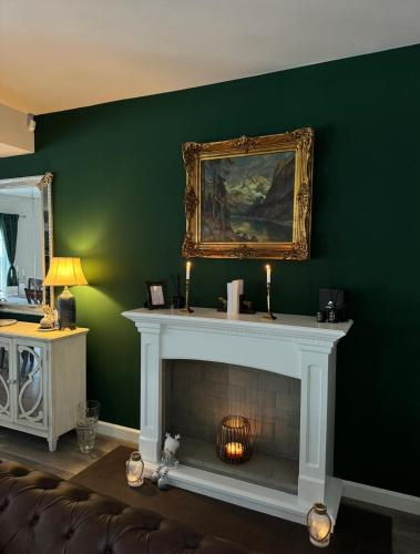 a fireplace in a living room with a green wall at Forest House Retreat in Curtea de Argeş