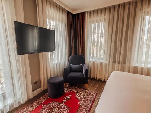 a room with a bed and a chair and a flat screen tv at Osmanli Cappadocia Hotel in Goreme
