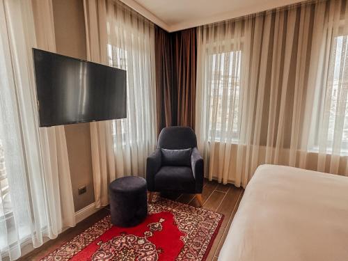 a hotel room with a bed and a chair and a television at Osmanli Cappadocia Hotel in Goreme