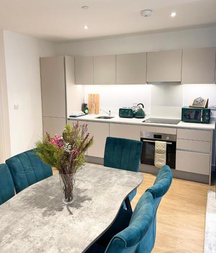 a kitchen with a table and some blue chairs at Urban Heaven with free parking in Bracknell