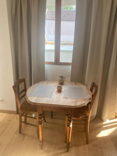 a wooden table with two chairs and a window at Grand studio lumineux à 10 min de Compiègne in Baugy